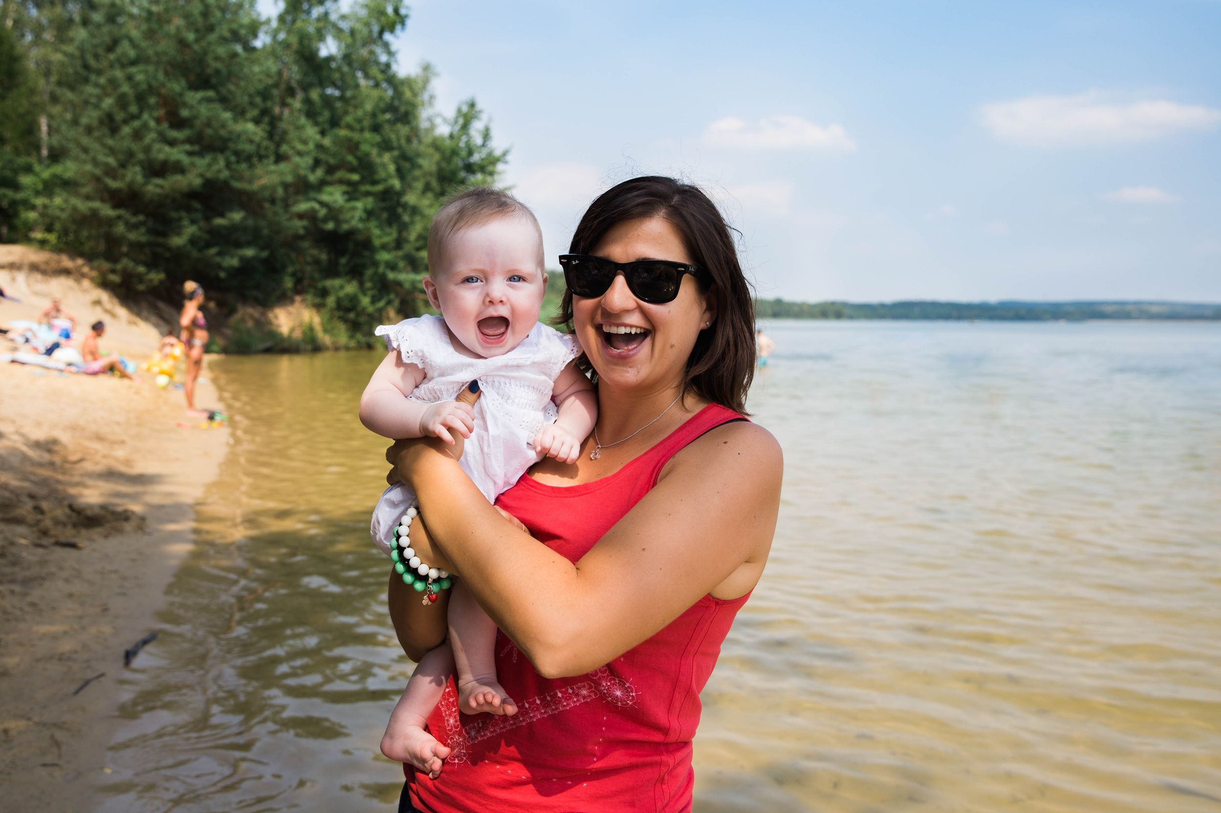 woman in red top holding smiling baby girl