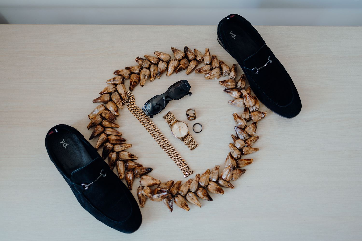 Wedding accessories arranged with black shoes and a decorative wreath.