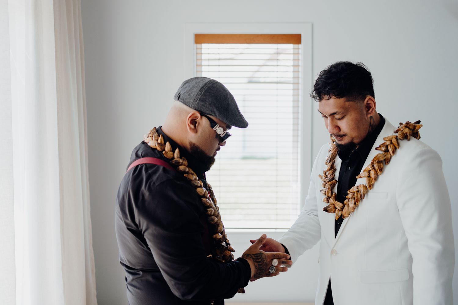 Two people share an intimate moment while wearing traditional Hawaiian leis during a formal ceremony.