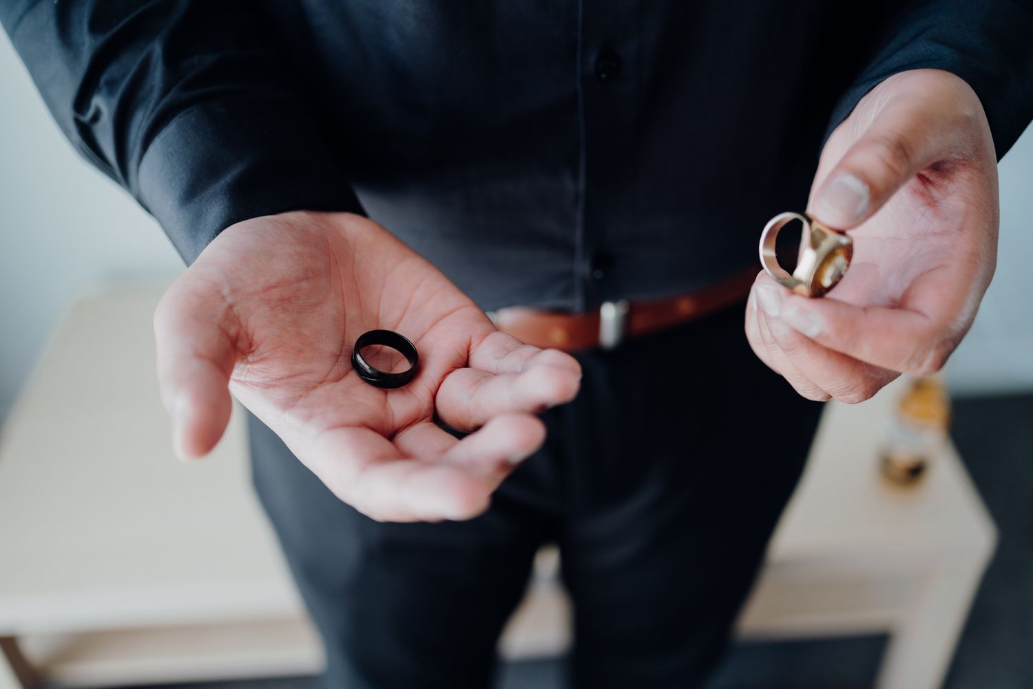 Hands displaying wedding rings against a dark formal suit.