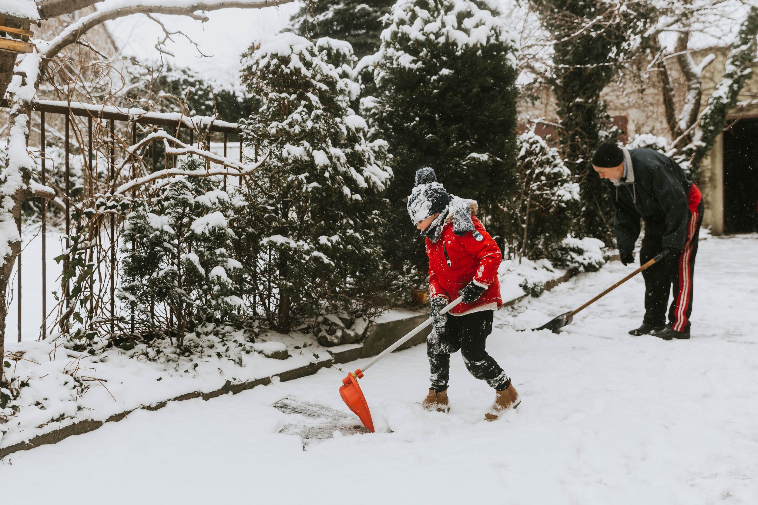 boy in red jacket and grandad clearing out snow