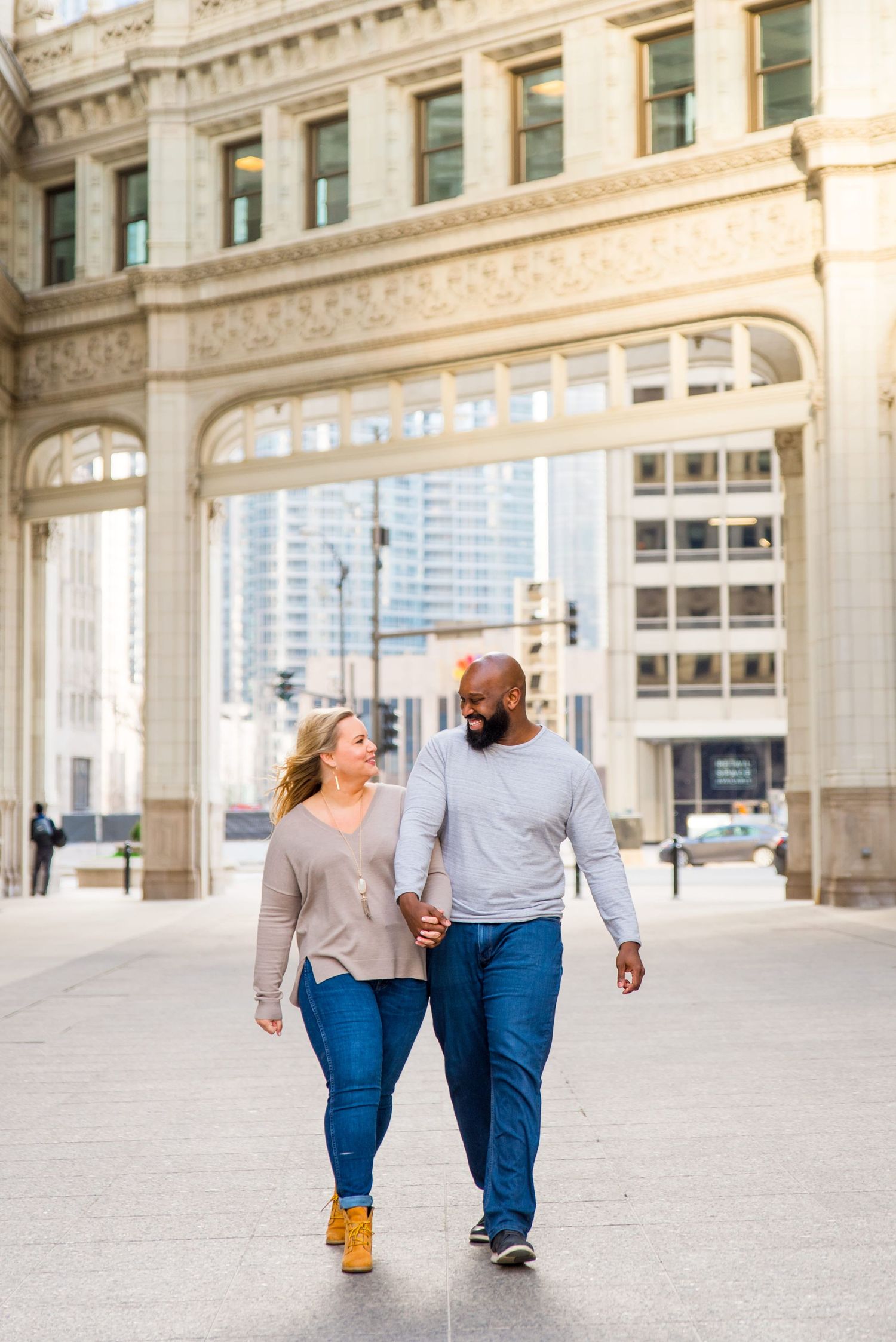 man and woman holding hands laughing at Wrigley Building Chicago engagement photos