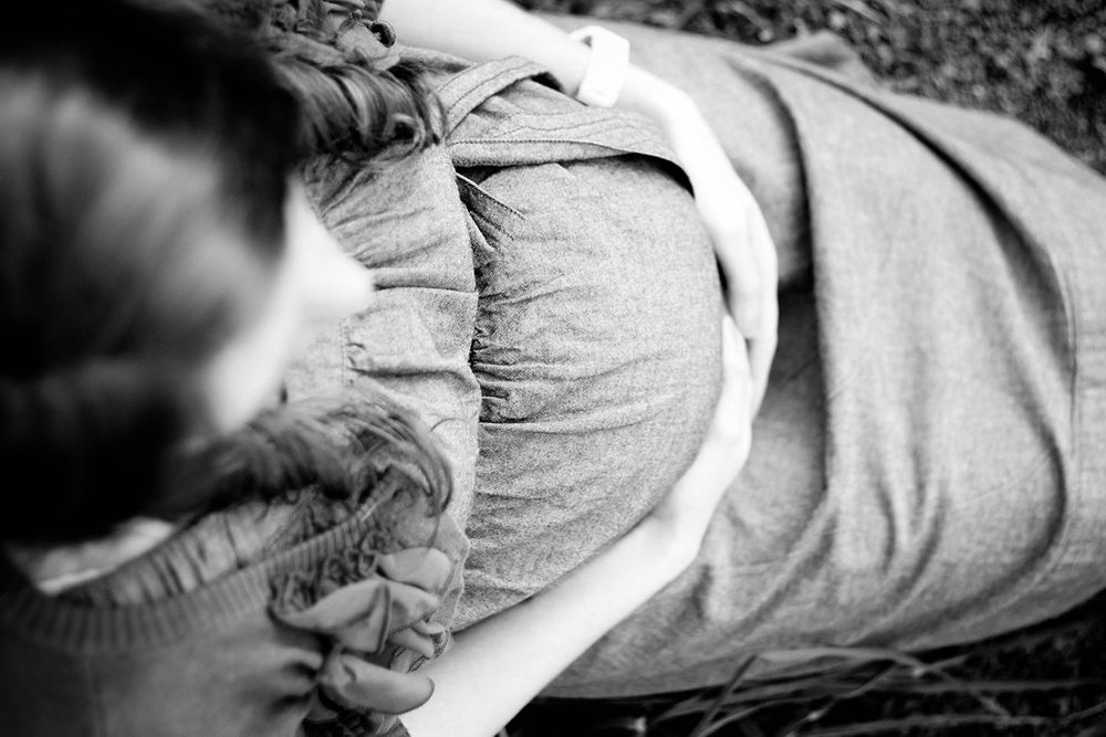 from the view above the pregnant woman you see her sitting with both arms holding her baby bump