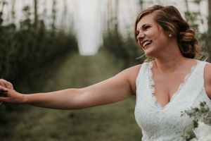 bride smiling in the rows of hops at climbing bines