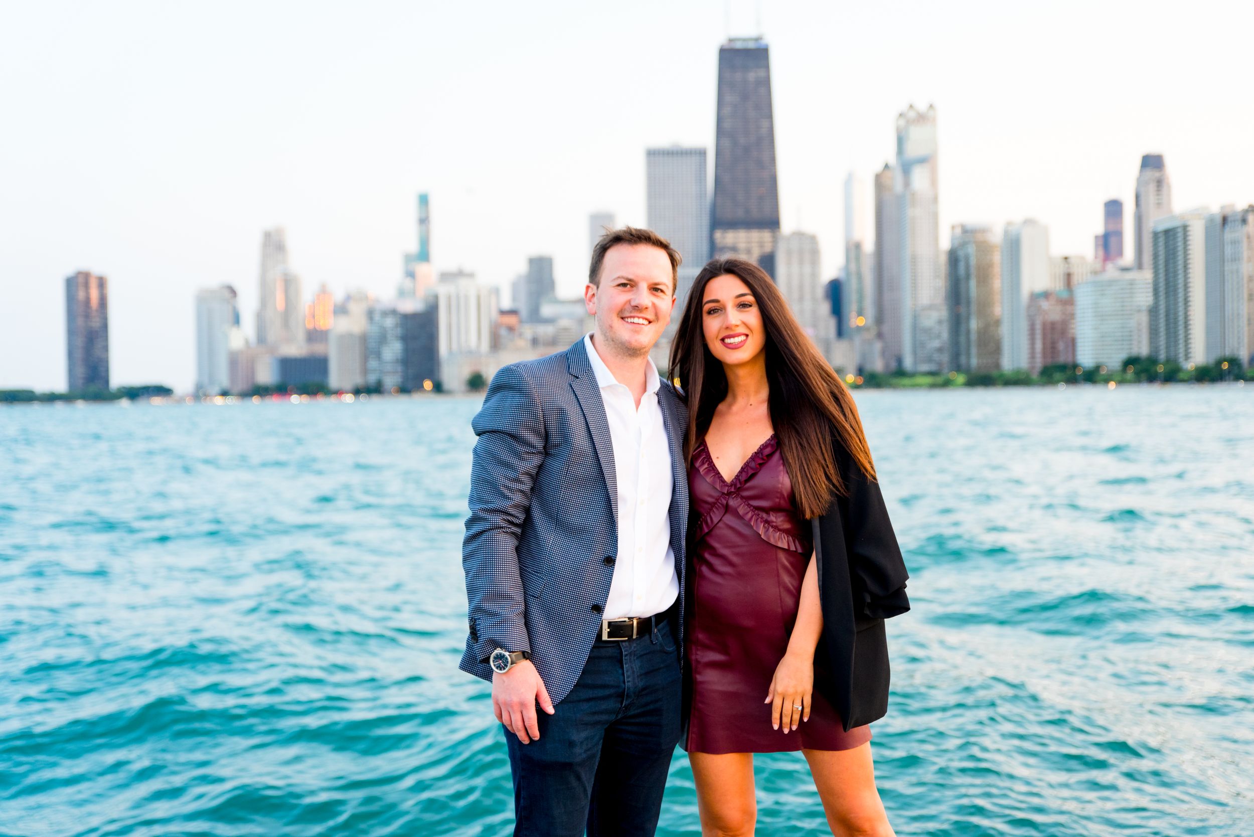 man and woman smiling holding hands in front of Chicago skyline after Chicago proposal