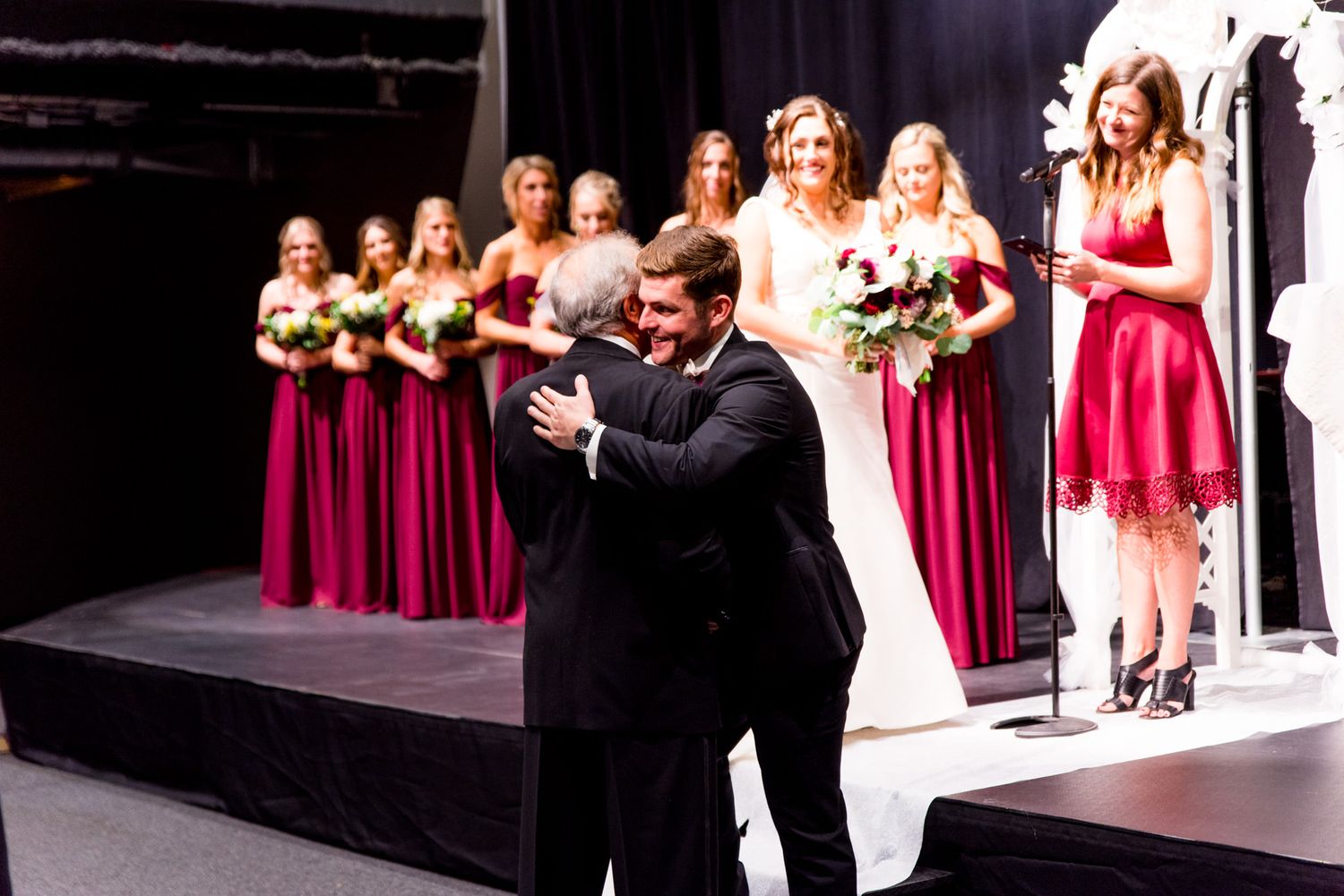 chicago bridesmaids wearing maroon watch groom hug father in law