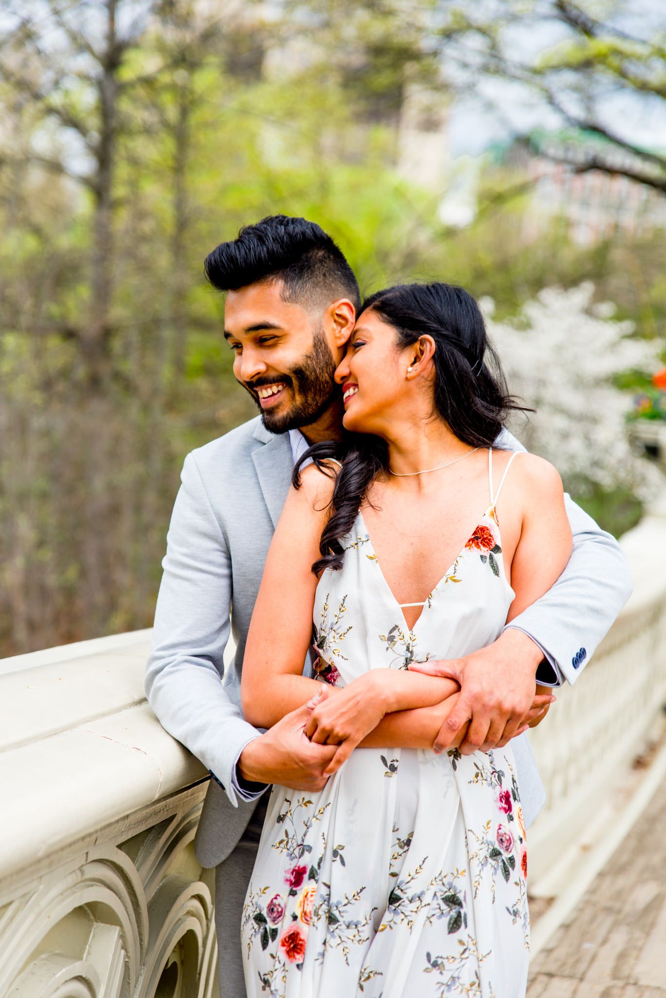 Young couple hugging and laughing on bow bridge Central Park engagement photos in NYC