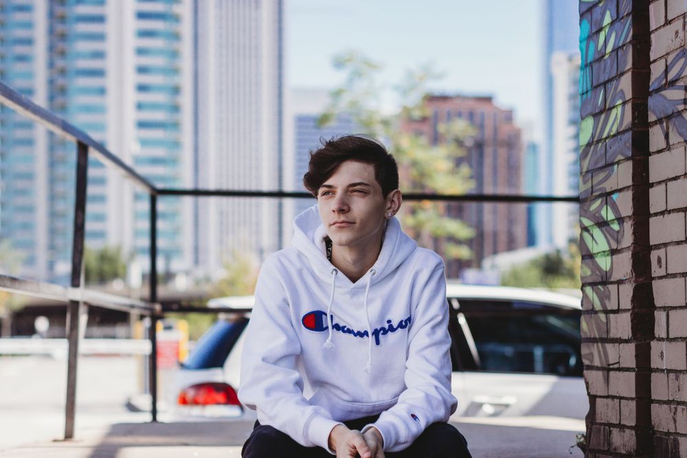 Senior boy seating on the stairs by cars wearing a white hoodie Chicago lifestyle session