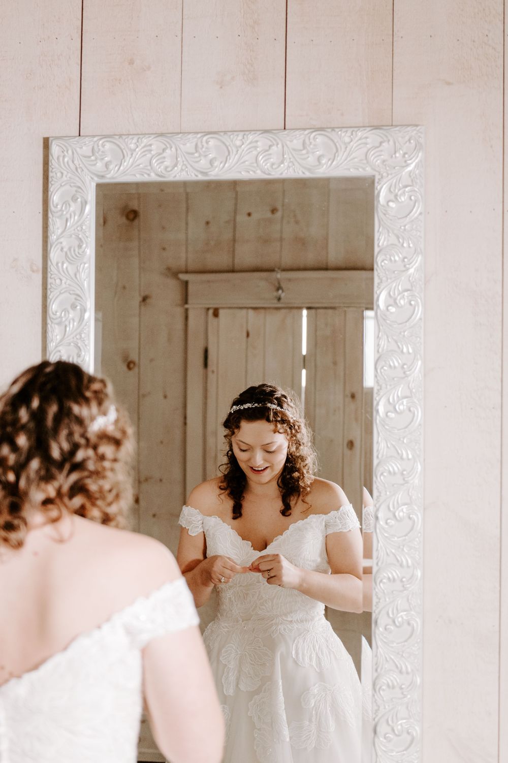 Bride getting ready for wedding day in front of mirror