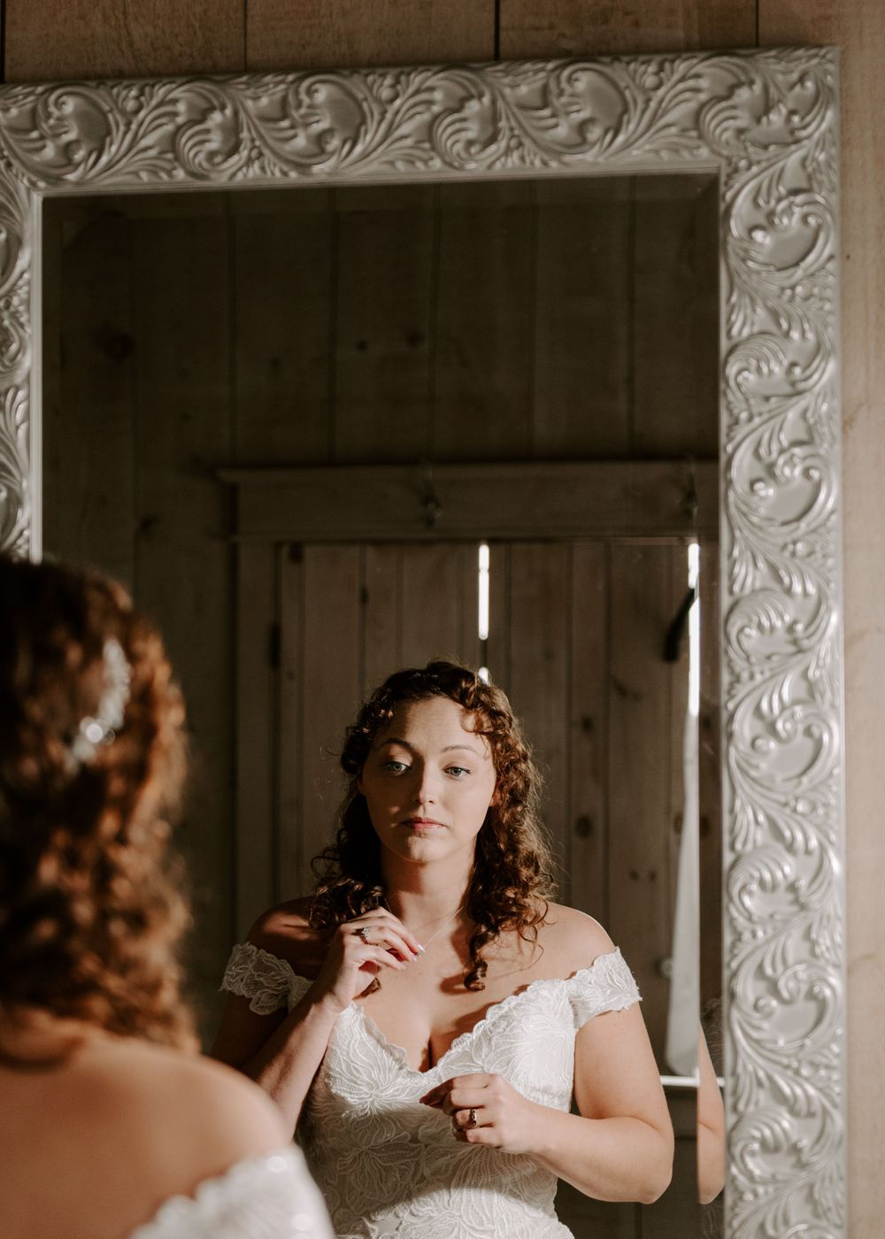 Bride getting ready for wedding day in front of mirror