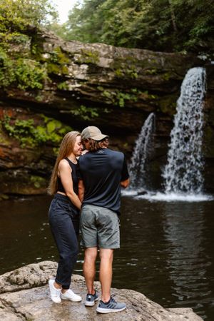 Couple cuddles together in front of Savage Falls, one of the best places to elope in Tennessee.