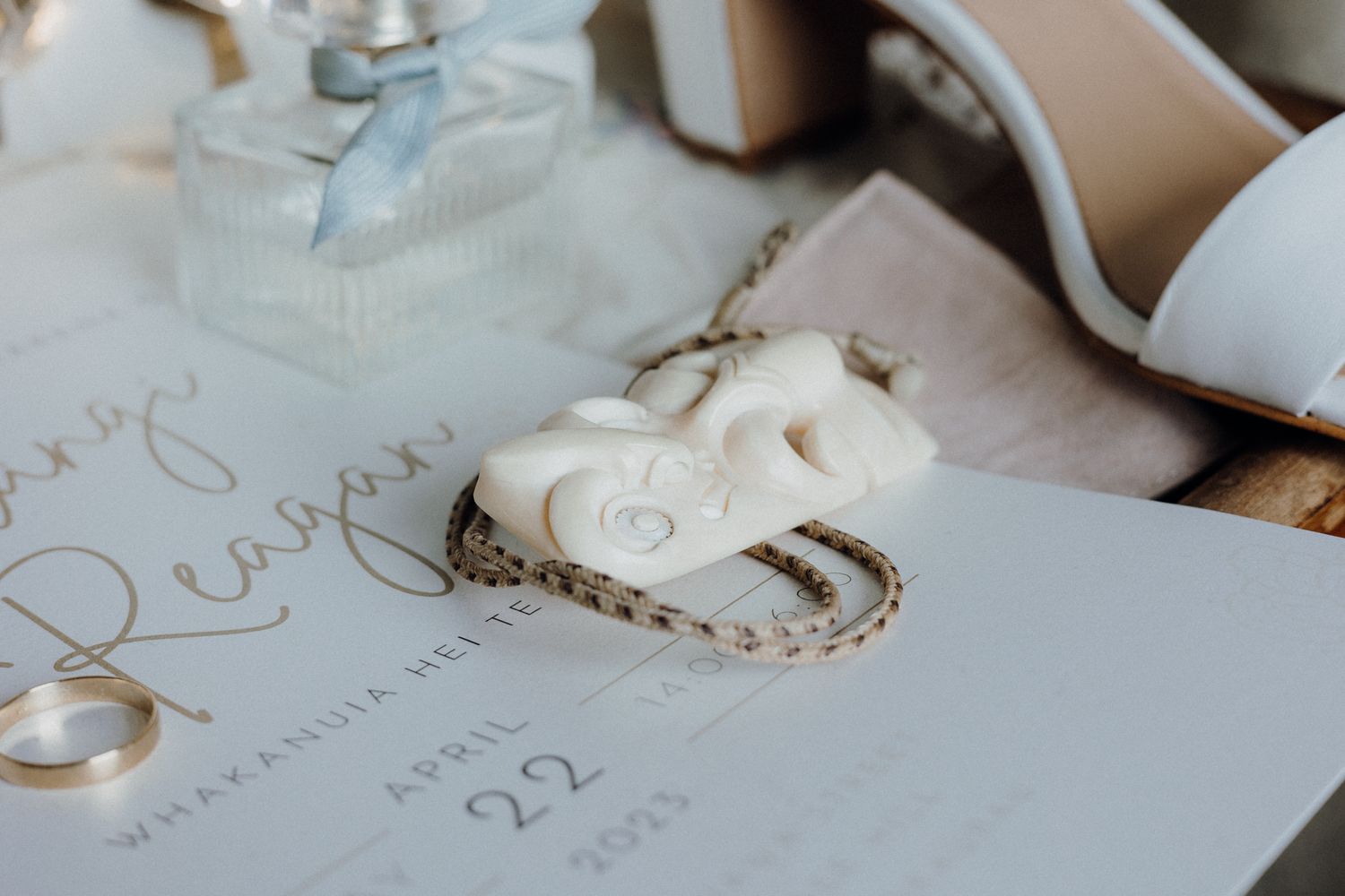 Close-up of wedding rings and invitation details in soft natural lighting.