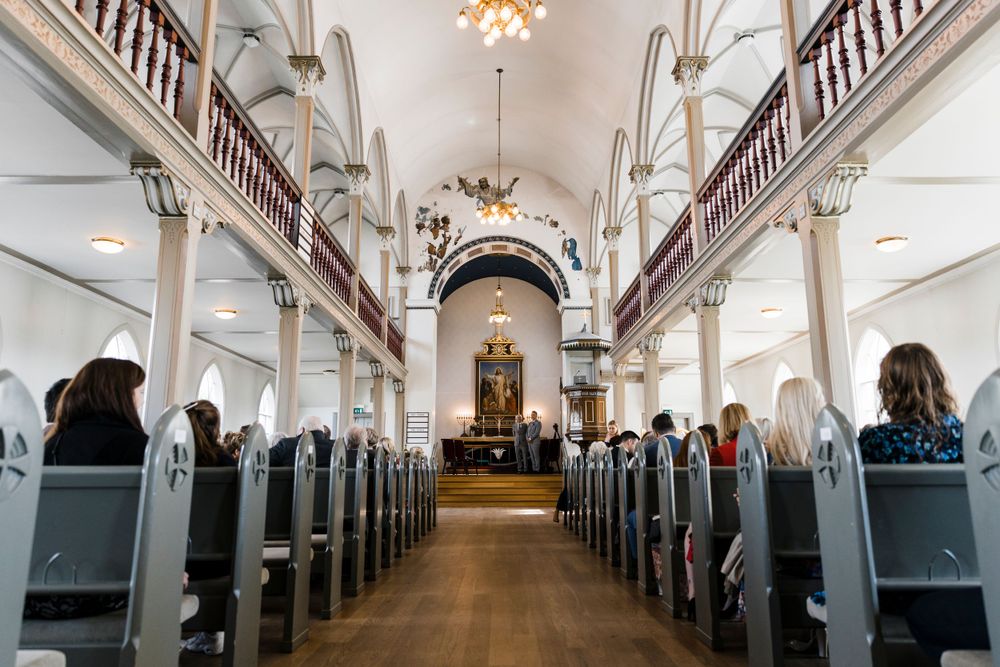 Interior of traditional white church with vaulted ceilings, wooden pews, and grand pipe organ.