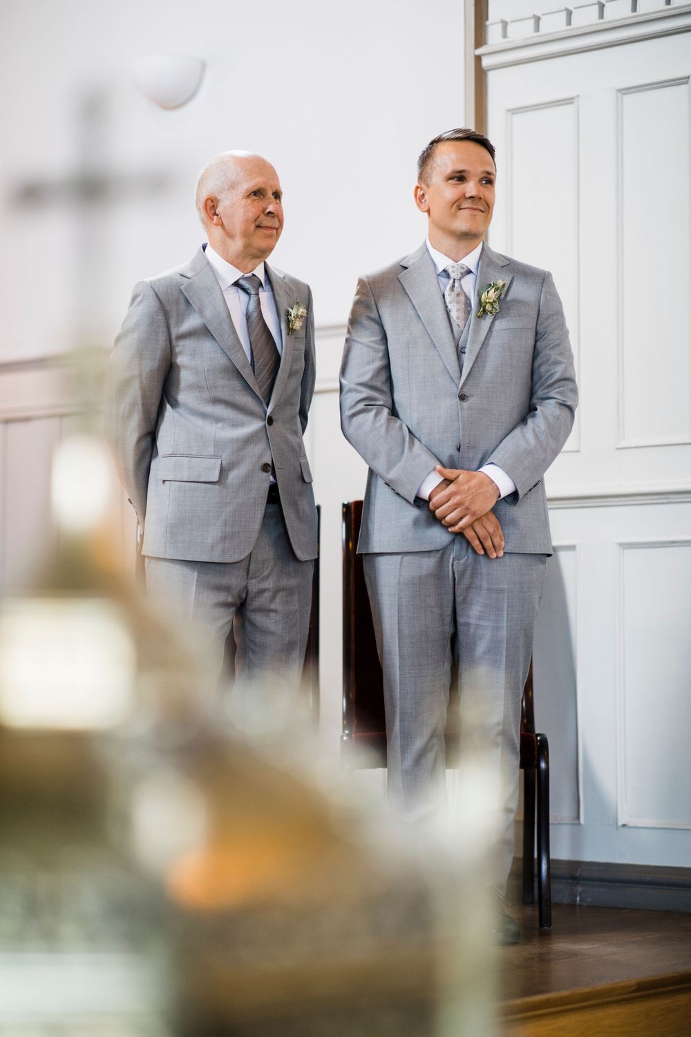 Two people in matching gray suits standing at the front of a church.