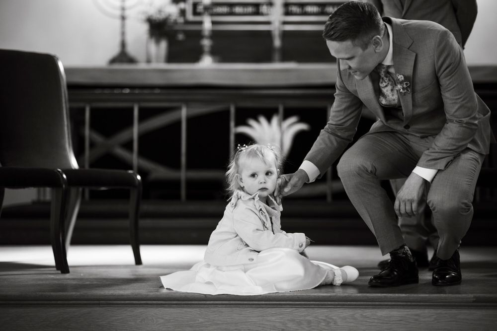 Sweet moment between a toddler in white dress and someone in formal attire.