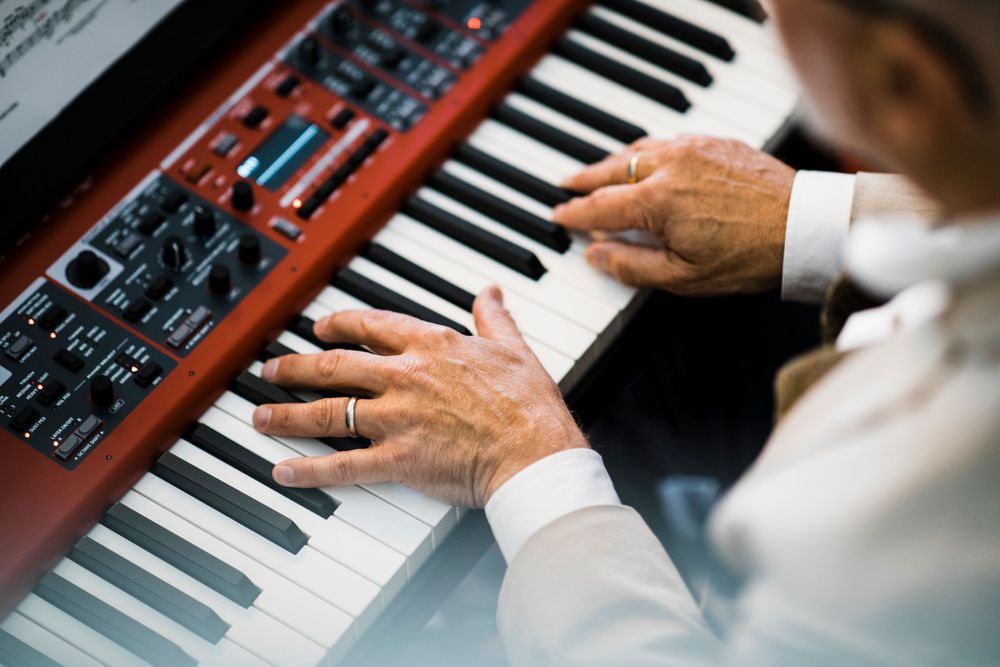 Close-up shot of hands playing a Nord stage piano keyboard.
