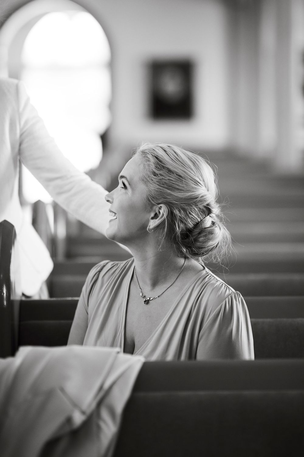 Side profile of someone sitting in a church pew looking up with an elegant hairstyle.