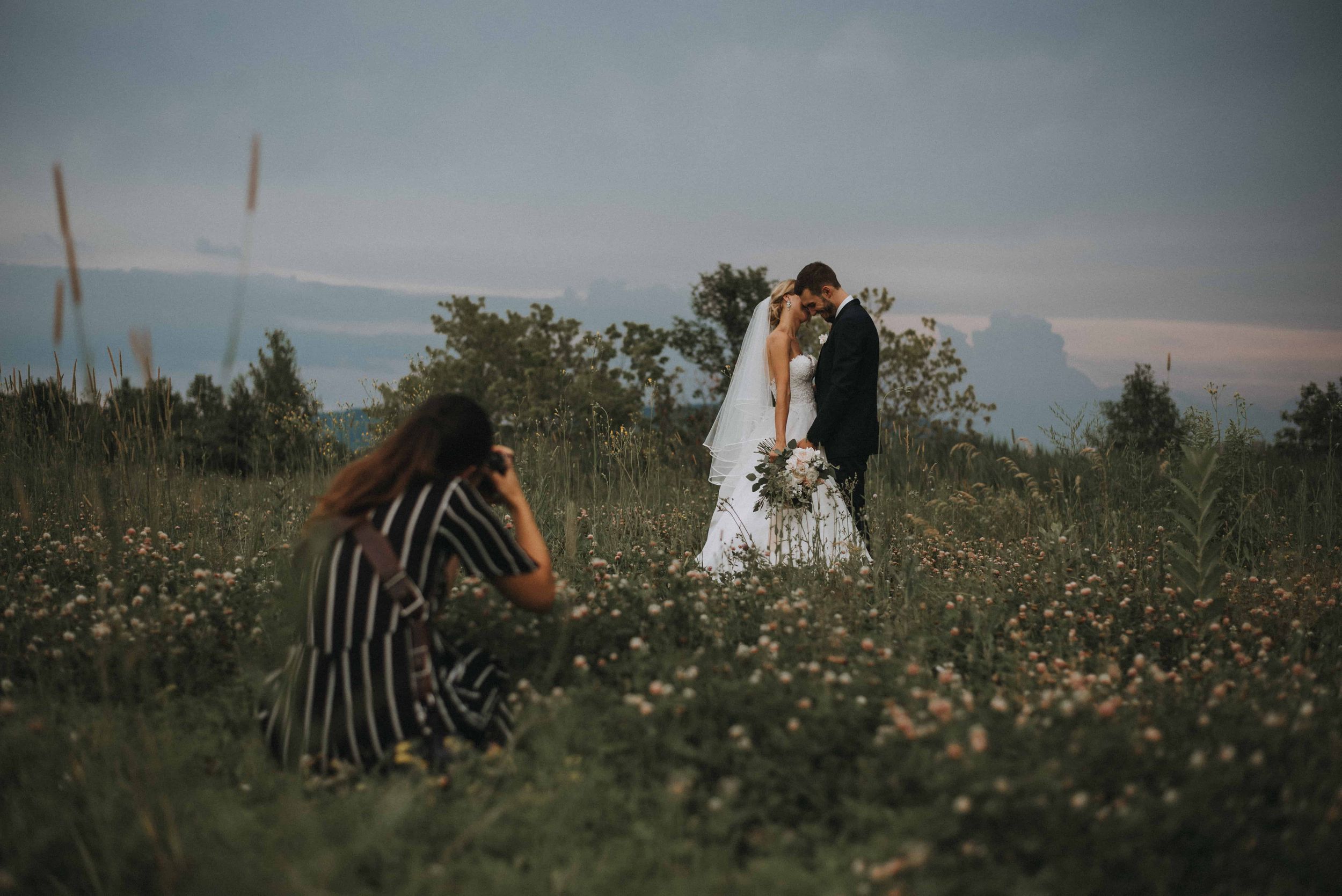 Raphaëlle Granger laying down in a flower field to get the perfect angle for this wedding session