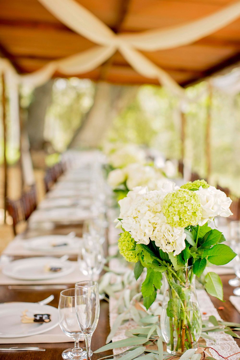 centerpieces with place settings on a long table for a wedding reception