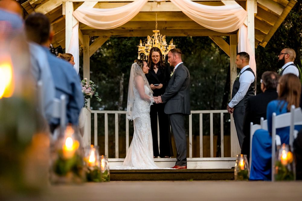 Married couple in front of officiant during wedding holding hands by Jay Grubb Photography