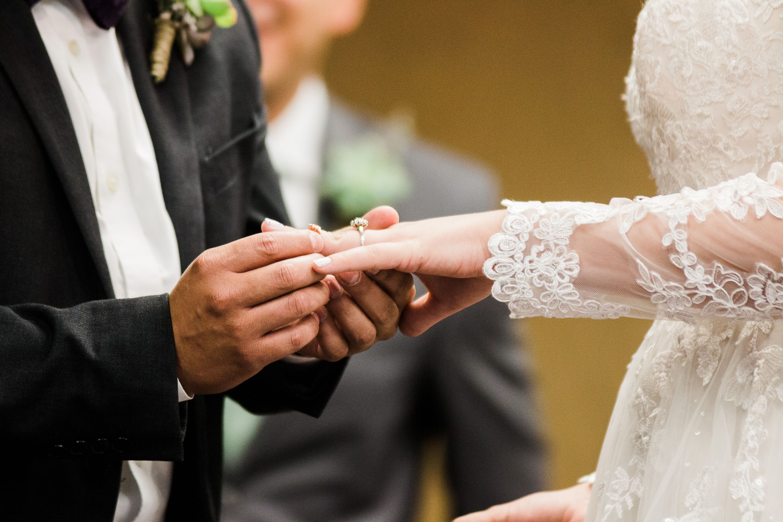 Groom slides ring onto bride's finger at Kingdom Hall wedding