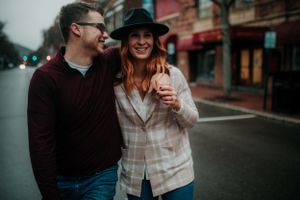 couple walking down the middle of market street smiling holding hands