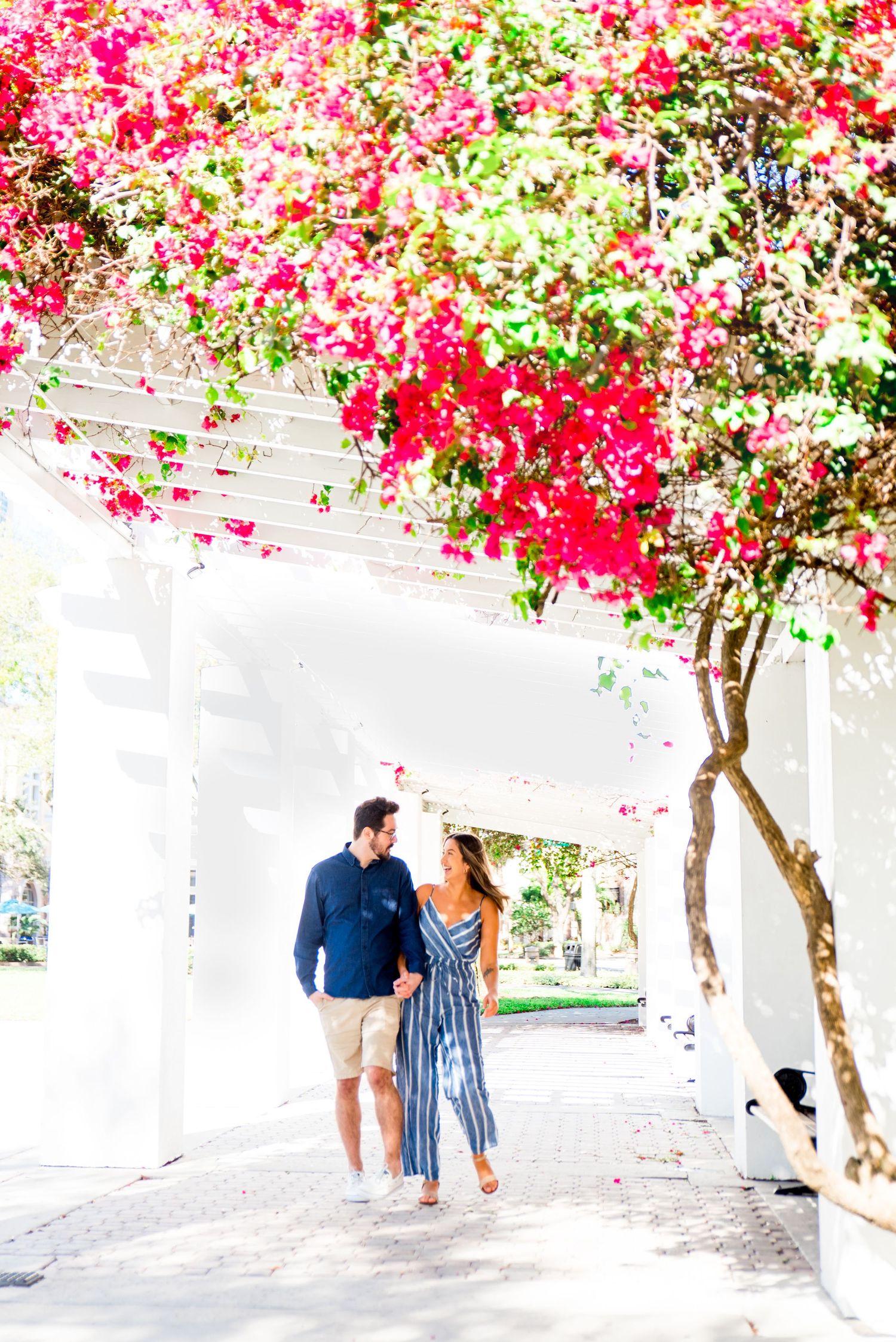 young couple in blue outfits walking and laughing at Vinoy Park St Pete engagement photos