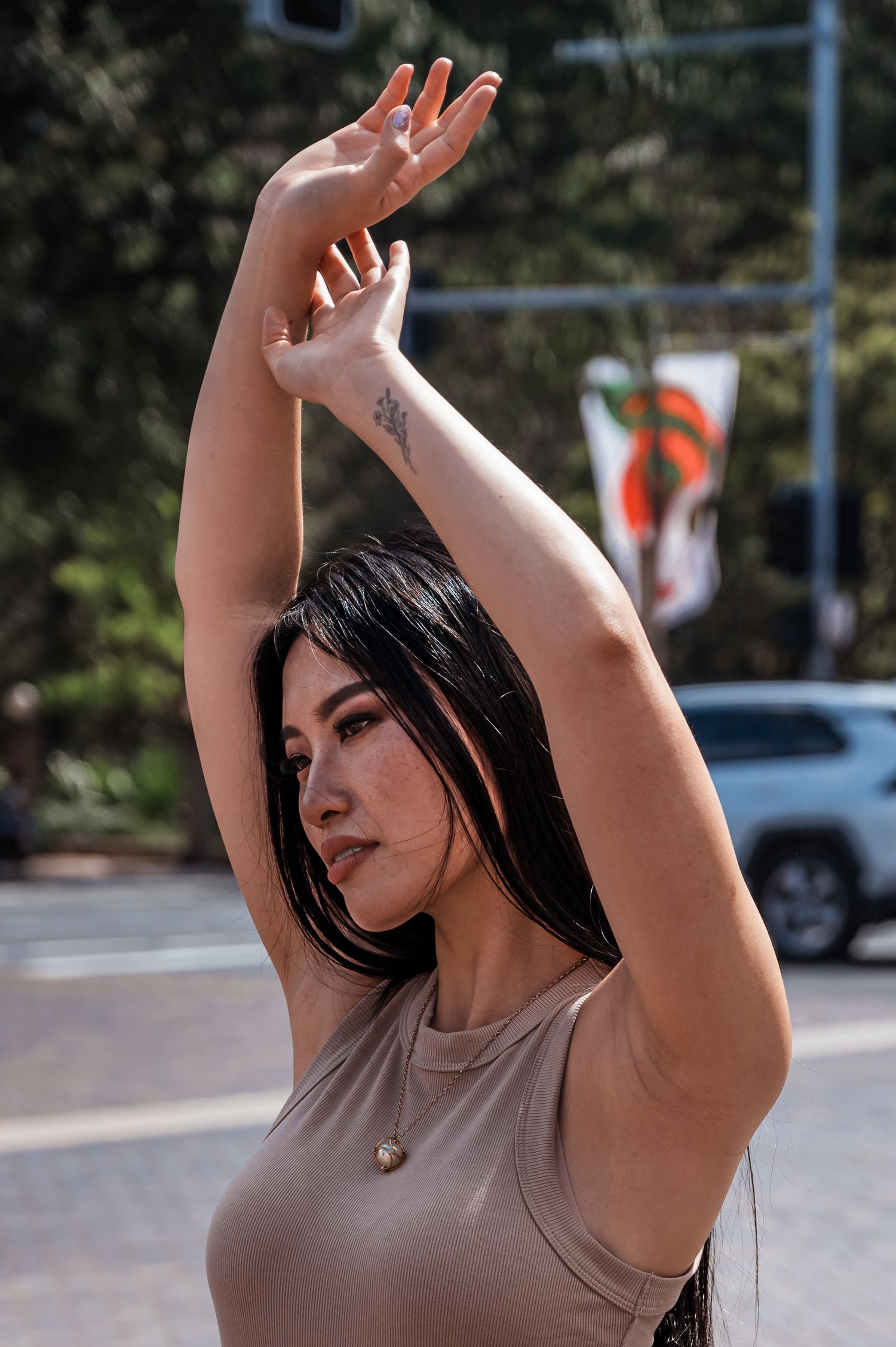 Female model posing with her arms raised above her head in Sydney city centre. SIX84 Photography, Portrait Photography, Sydney