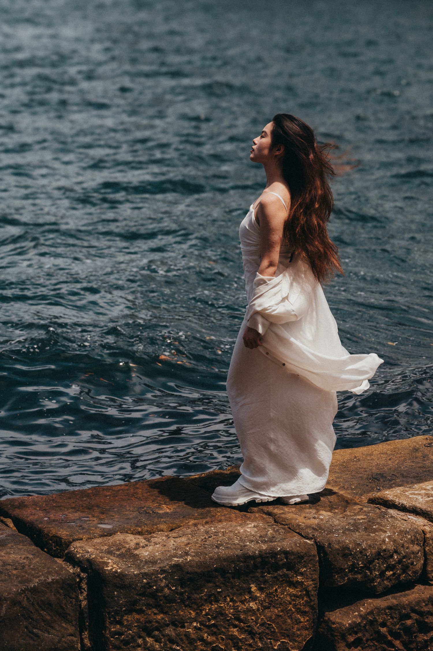 Woman in a white dress standing by the water, with the Sydney Opera House in the background. SIX84 Photography, Portrait Photography, Sydney