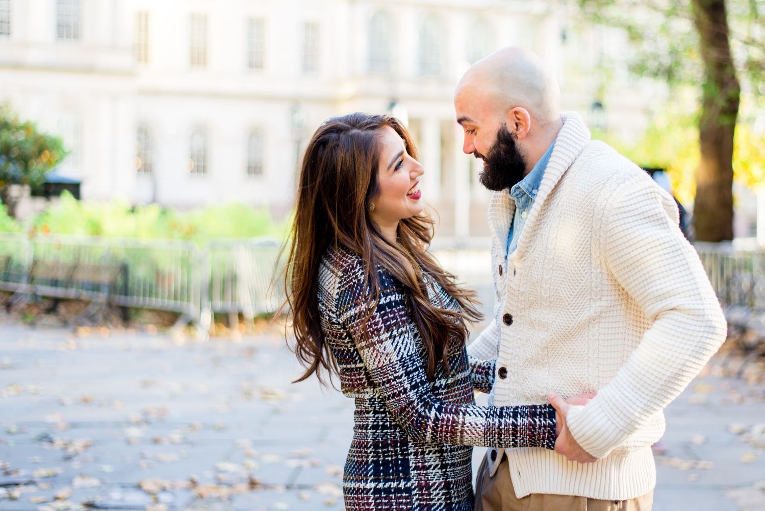 young engaged couple in fall clothes hold hands and smile at each other for NYC City Hall Engagement Pictures