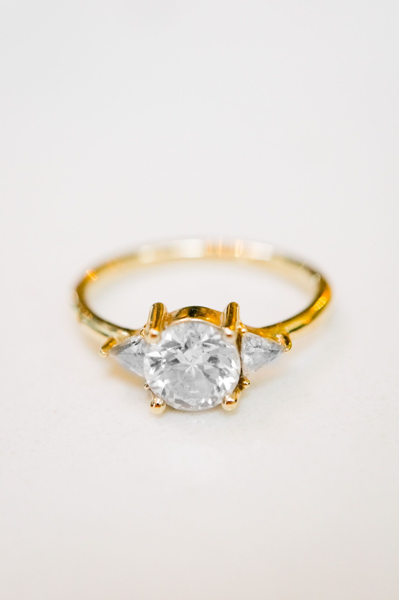 gold band engagement ring with round diamond and two triangle side stone diamonds