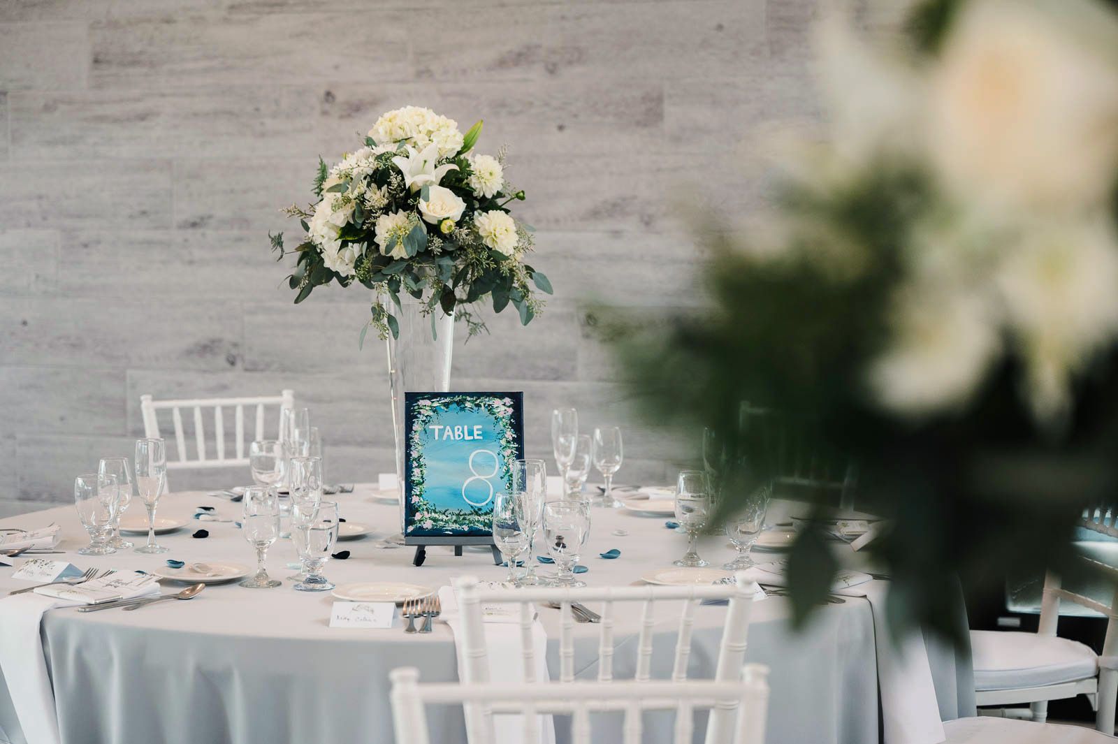 reception table center piece with white flowers and blue hand-painted table numbers
