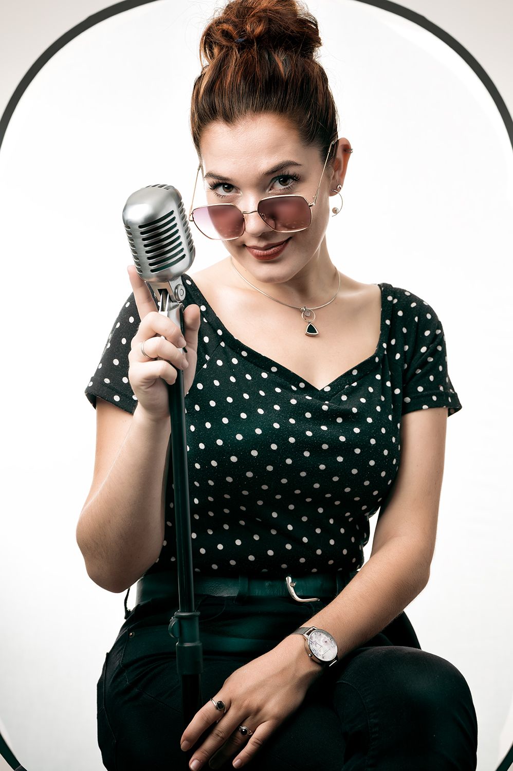 Jeune femme tenant un micro vintage et habillée à la mode des années 50, regardant l'objectif