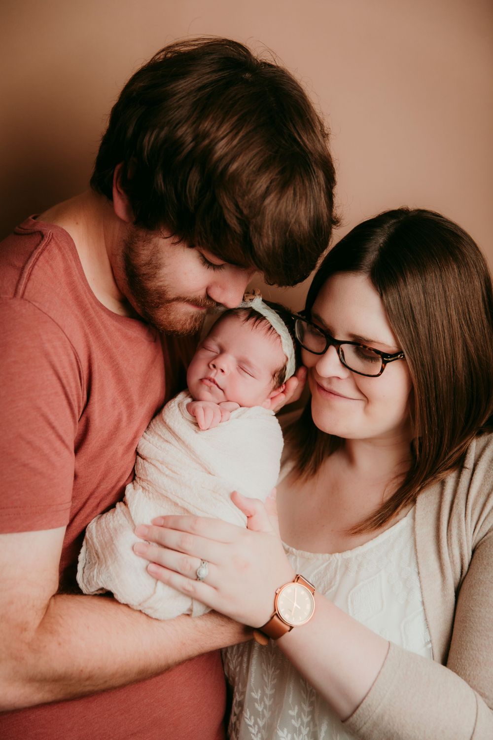 mom and dad holding baby girl neutral color scheme