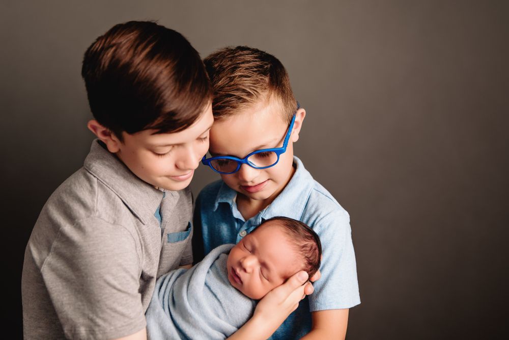 siblings holding their baby brother