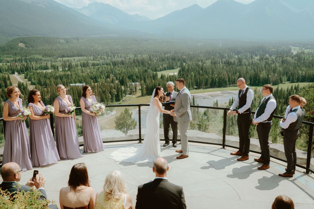 Wedding ceremony setup in a scenic mountainous backdrop with rows of chairs and floral decorations.