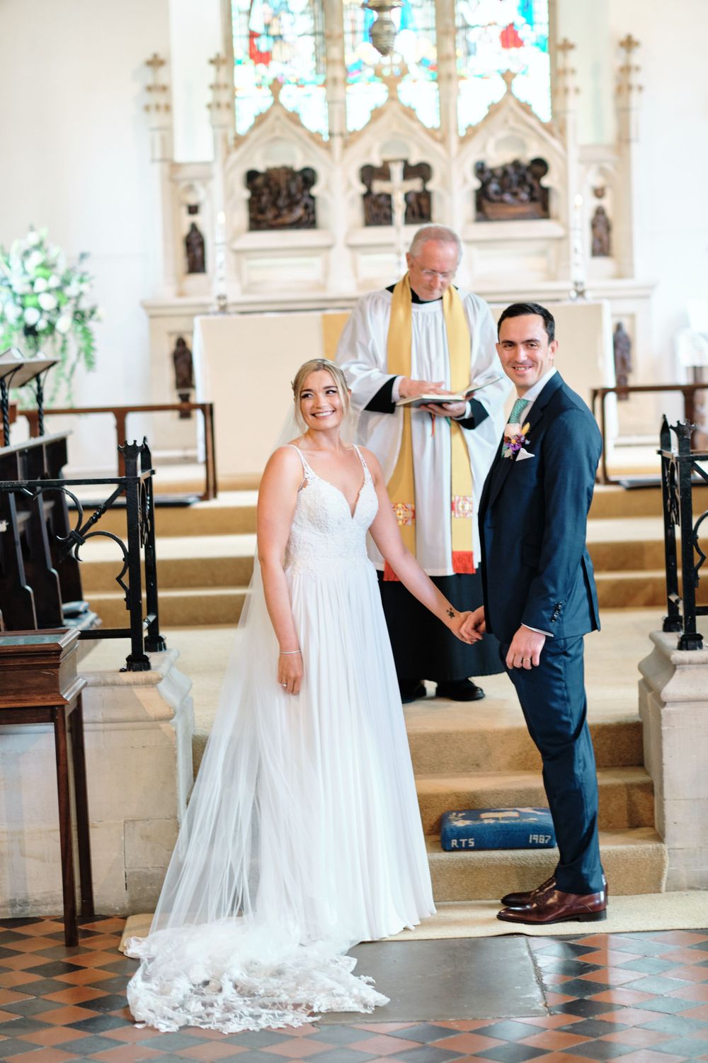 A wedding ceremony in a traditional church with stained glass windows and ornate altar.