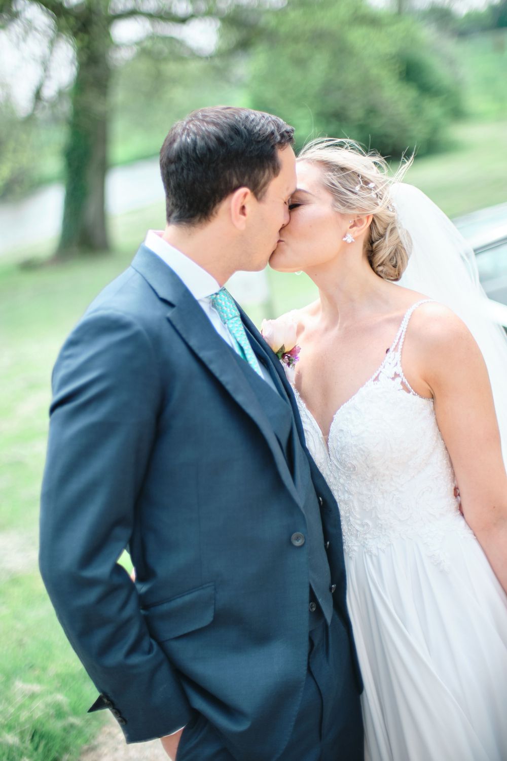 Intimate wedding moment captured during a tender kiss against a natural outdoor backdrop.