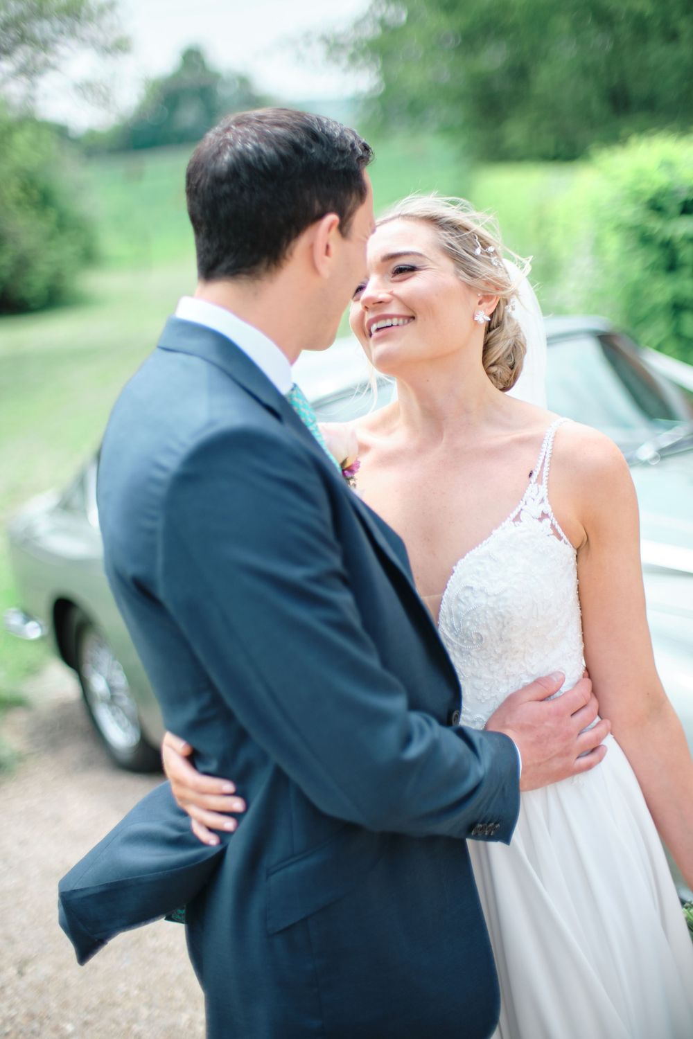 Joyful wedding moment shared between a couple against a lush green countryside backdrop.