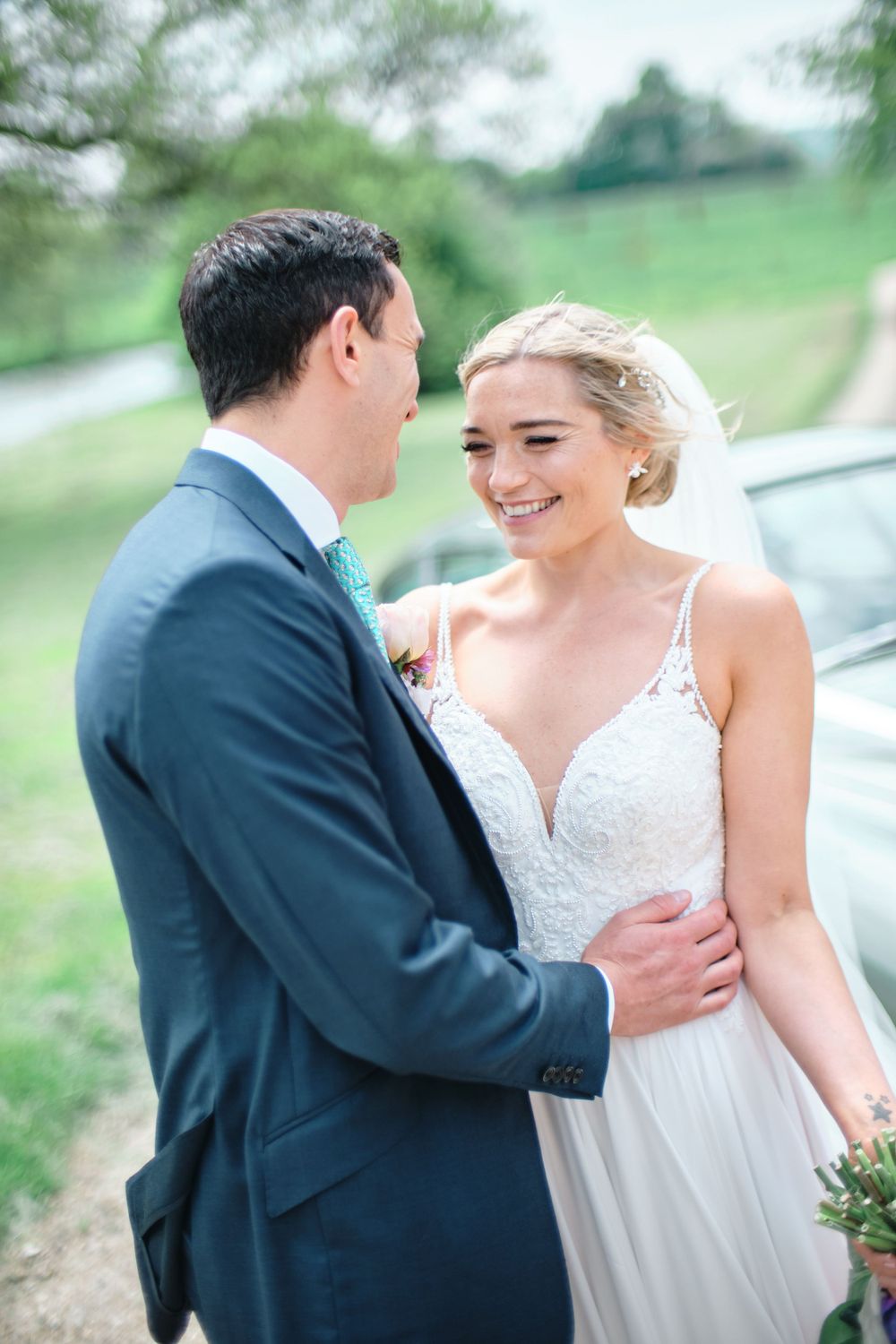 Candid moment of laughter and joy between newlyweds in an outdoor garden setting.