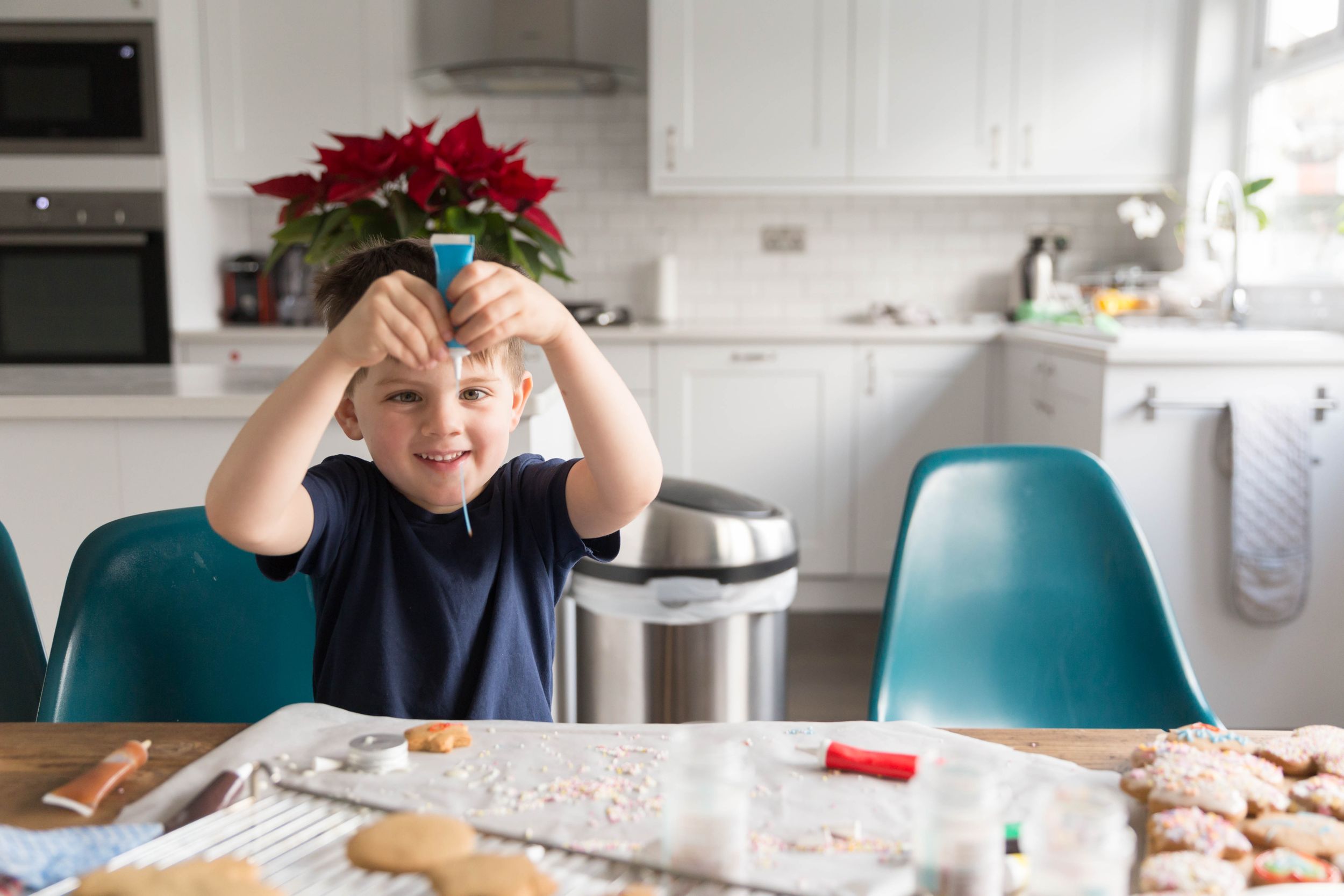 little boy holding blue icing tube in hands smiling