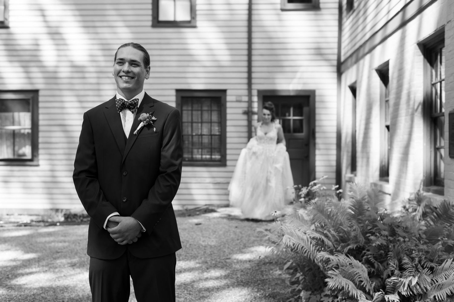 Black and white wedding photo showing traditional first look moment outside a white building.
