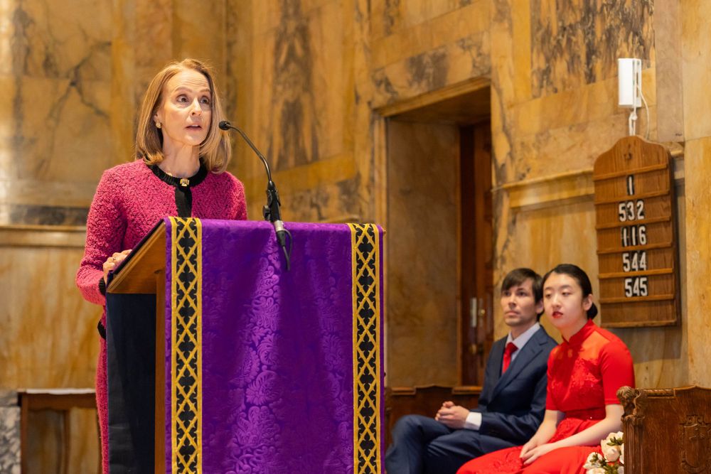 Speaker addressing audience from purple-draped podium in historic church setting.