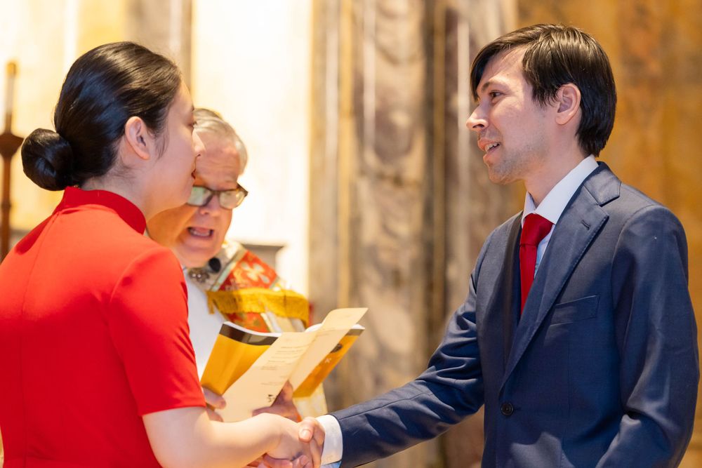 Formal ceremony participants interacting in ornate church setting.