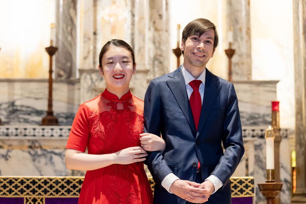 Formal couple posing in traditional attire inside historic church.