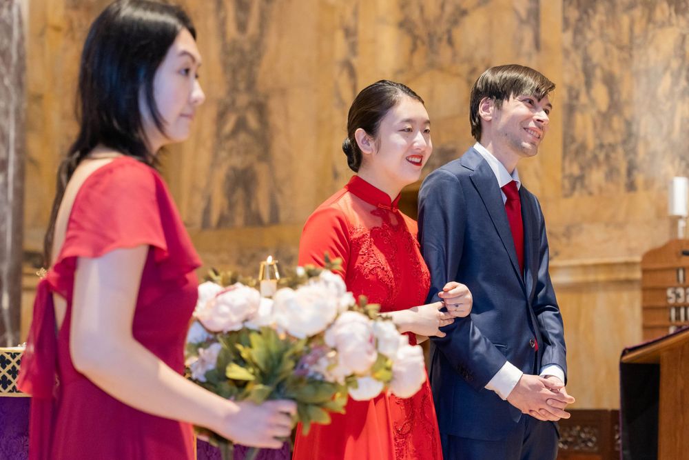Ceremony participants in formal attire inside ornate church interior.