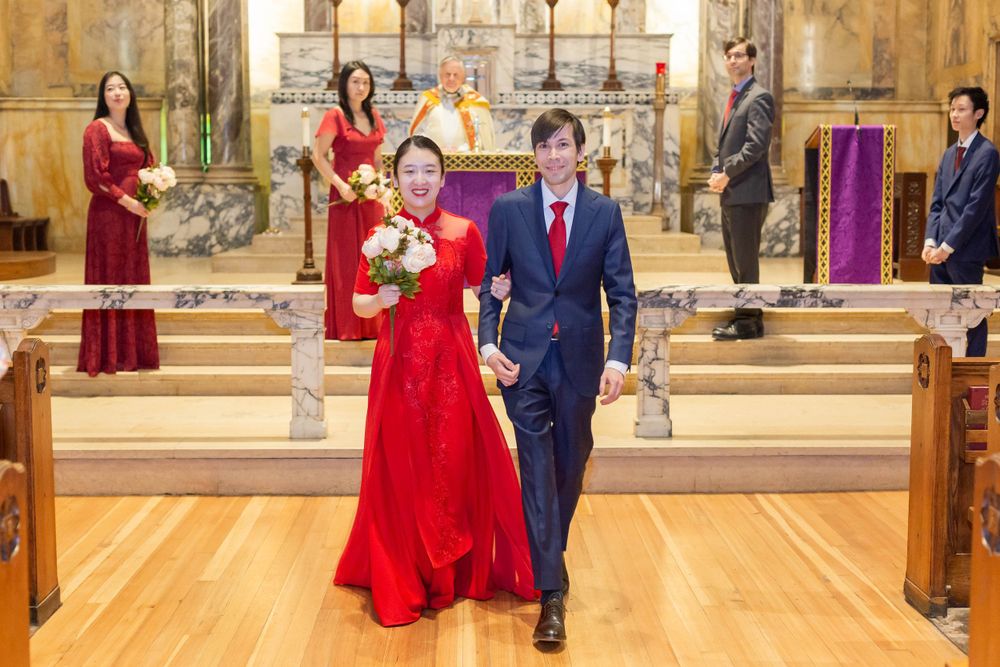 A couple walks down the church aisle together with guests looking on during their ceremony.