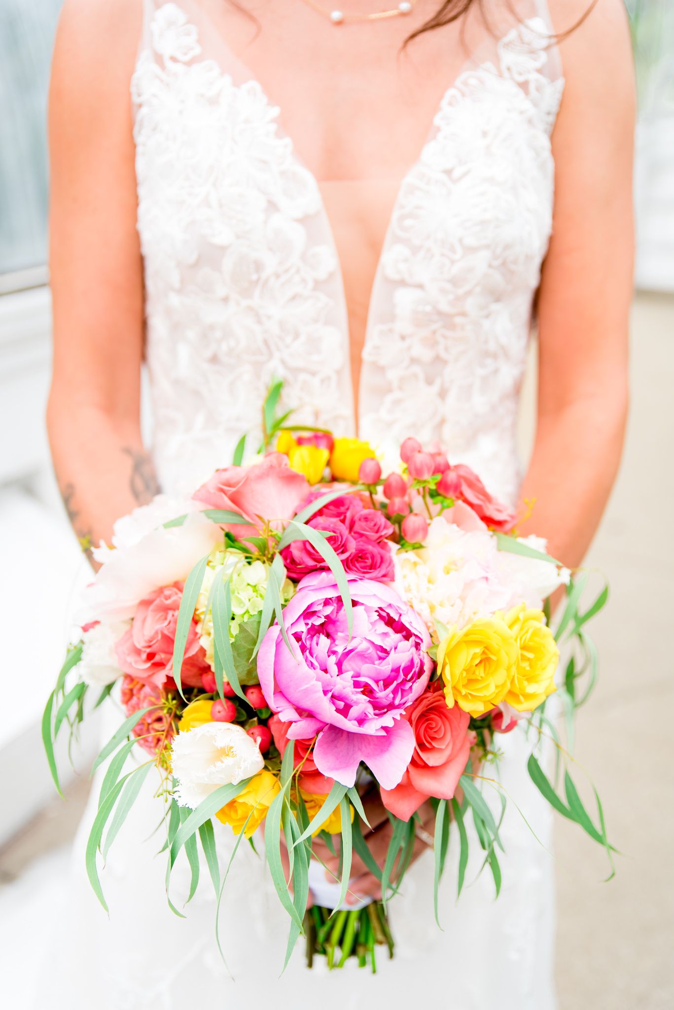 bride in Kelly Faetanini Serafina gown holding a pink, yellow, and green wedding bouquet at Krohn Conservatory