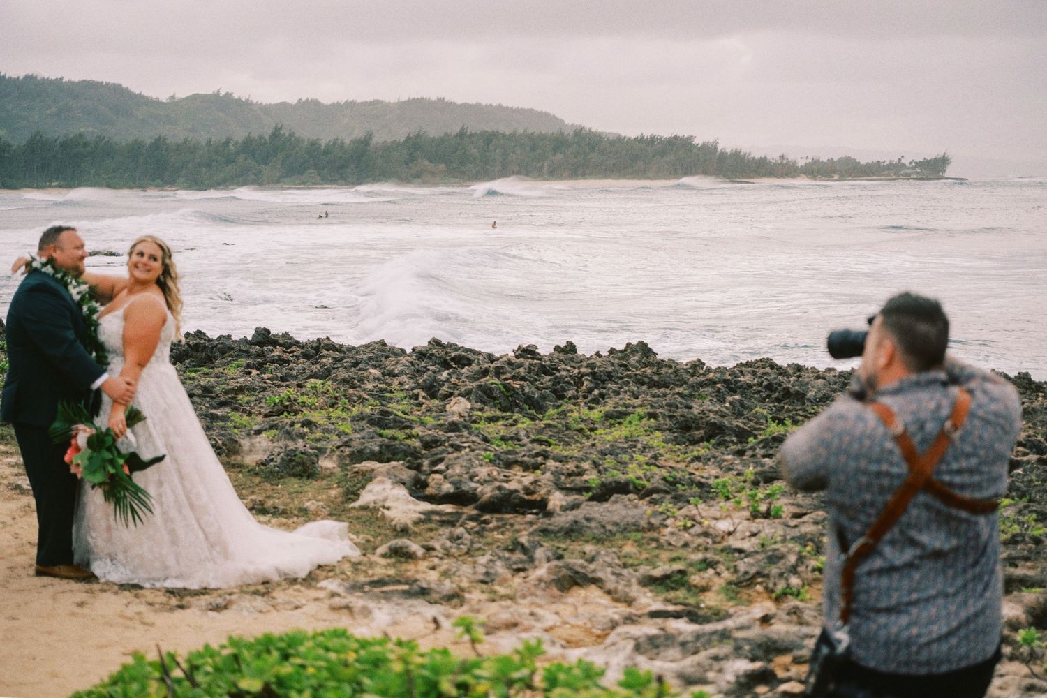 Beach wedding photoshoot on rocky Hawaiian coastline.