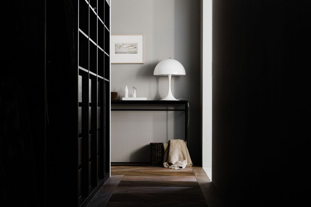 Modern interior with a white dome lamp and black shelving unit against a gray wall creating a minimalist aesthetic.